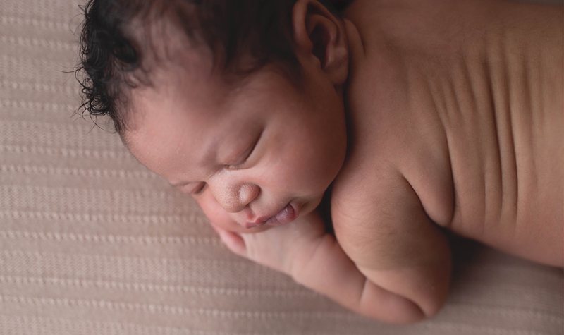 Newborn Photography, close up of baby laying on a tan blanket