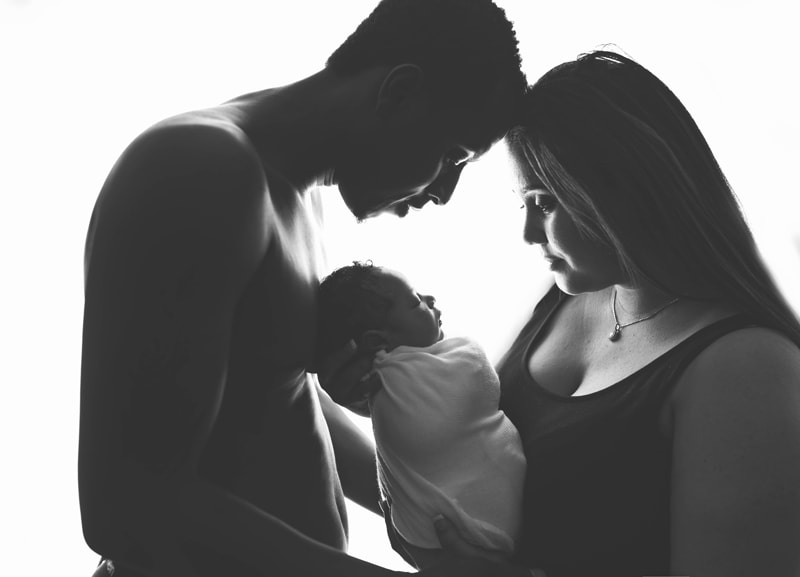 Newborn Photography, mother and father holding baby between them on white background