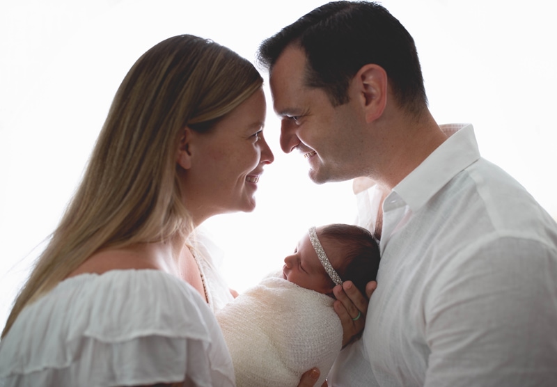 Newborn Photography, mother and father with baby on a white background