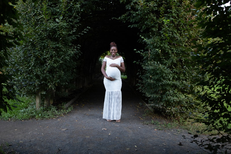 Maternity Photography, woman standing under a bush archway
