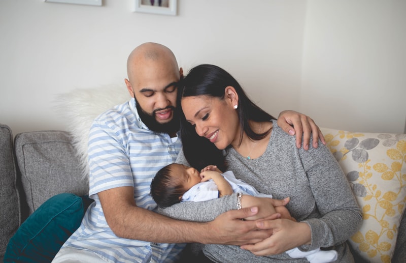 Newborn Photography, father and mother holding baby on couch