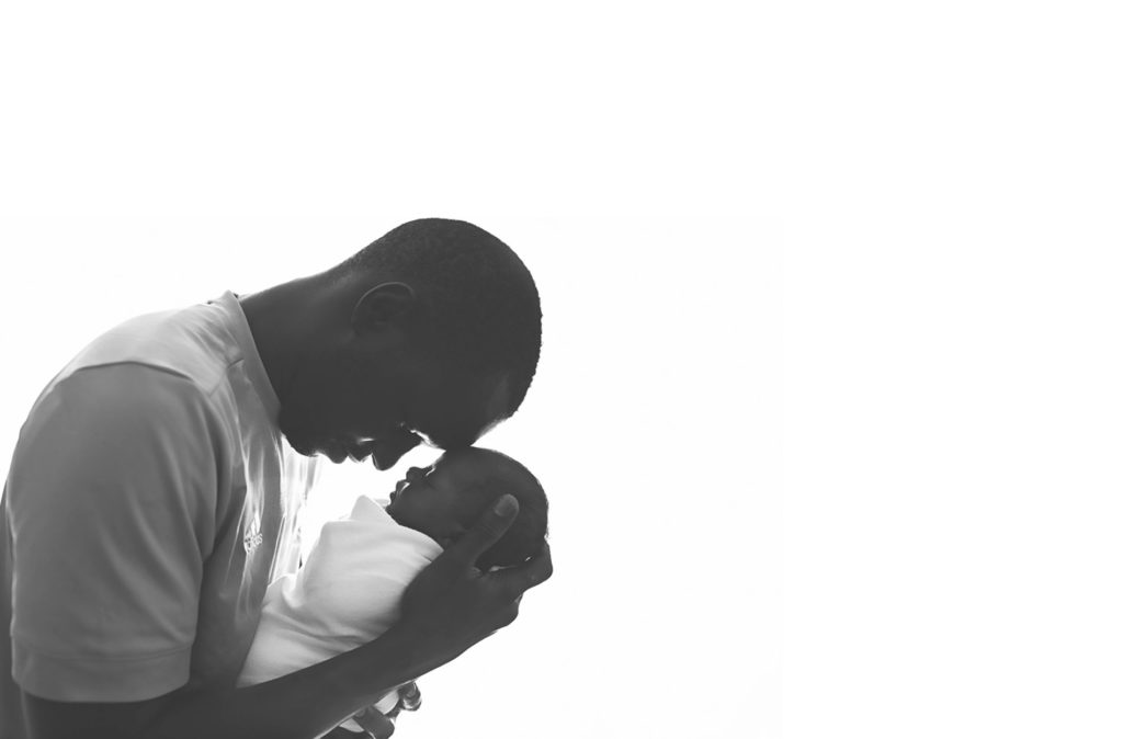 Newborn Photography, man holding a baby against a white background