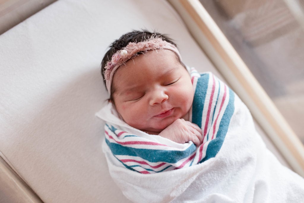 Newborn Photography, baby wrapped up in hospital with a bow headband on her head